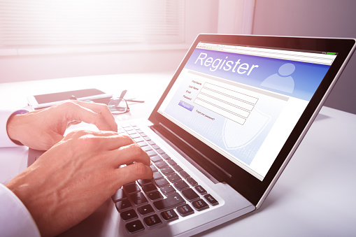 Businessman's Hand Filling Online Registration Form On Laptop